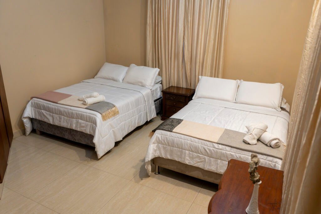 Habitación Victoria con camas de ropa blanca y cortinas doradas