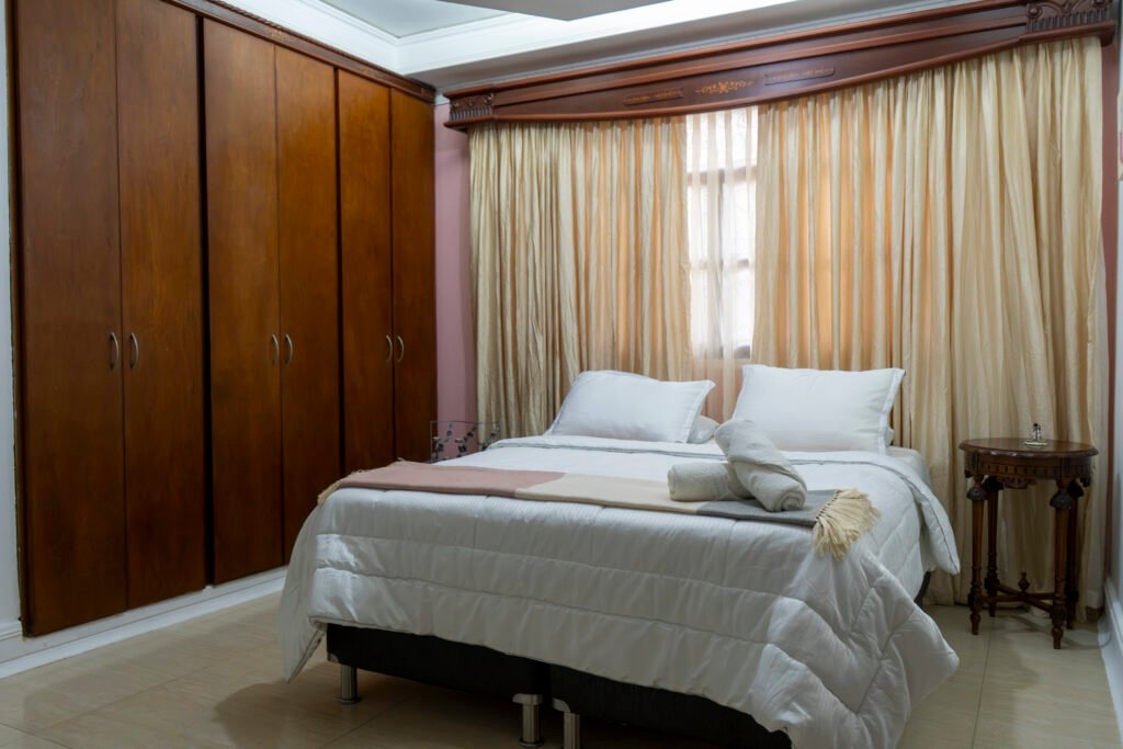 Habitación Jazmín con clóset de madera y ventana con cortinas