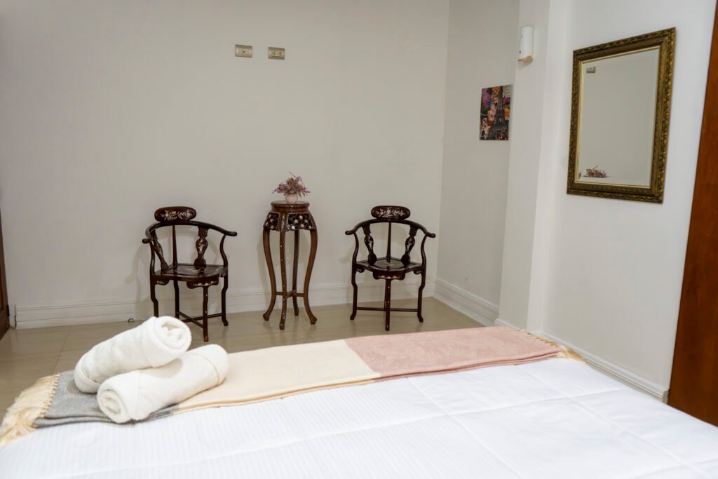 Rincón con sillas de madera y espejo en la habitación Jazmín