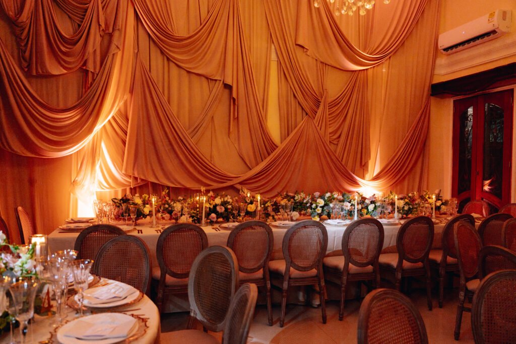 Salón decorado con telas, candelabro y mesas redondas para una celebración