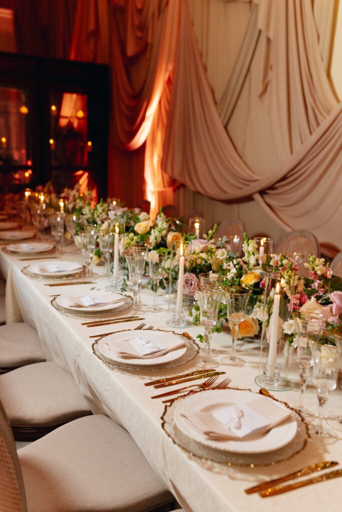 Mesa larga con arreglos florales y vajilla para un banquete