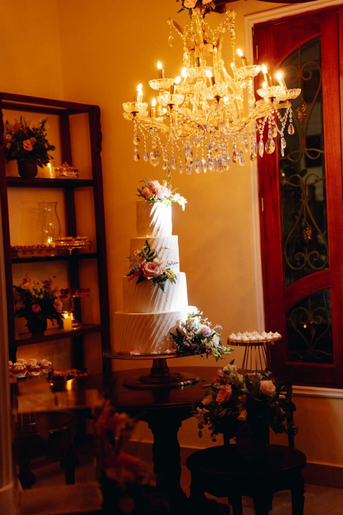 Mesa de postres con torta de bodas bajo un candelabro